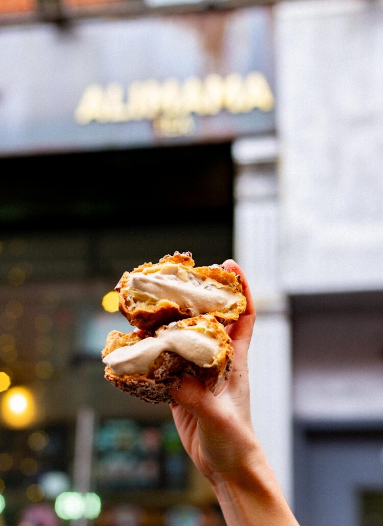 a Hand holding a black milk tea and boba cream puff from Alimama, one of the best desserts in Chinatown