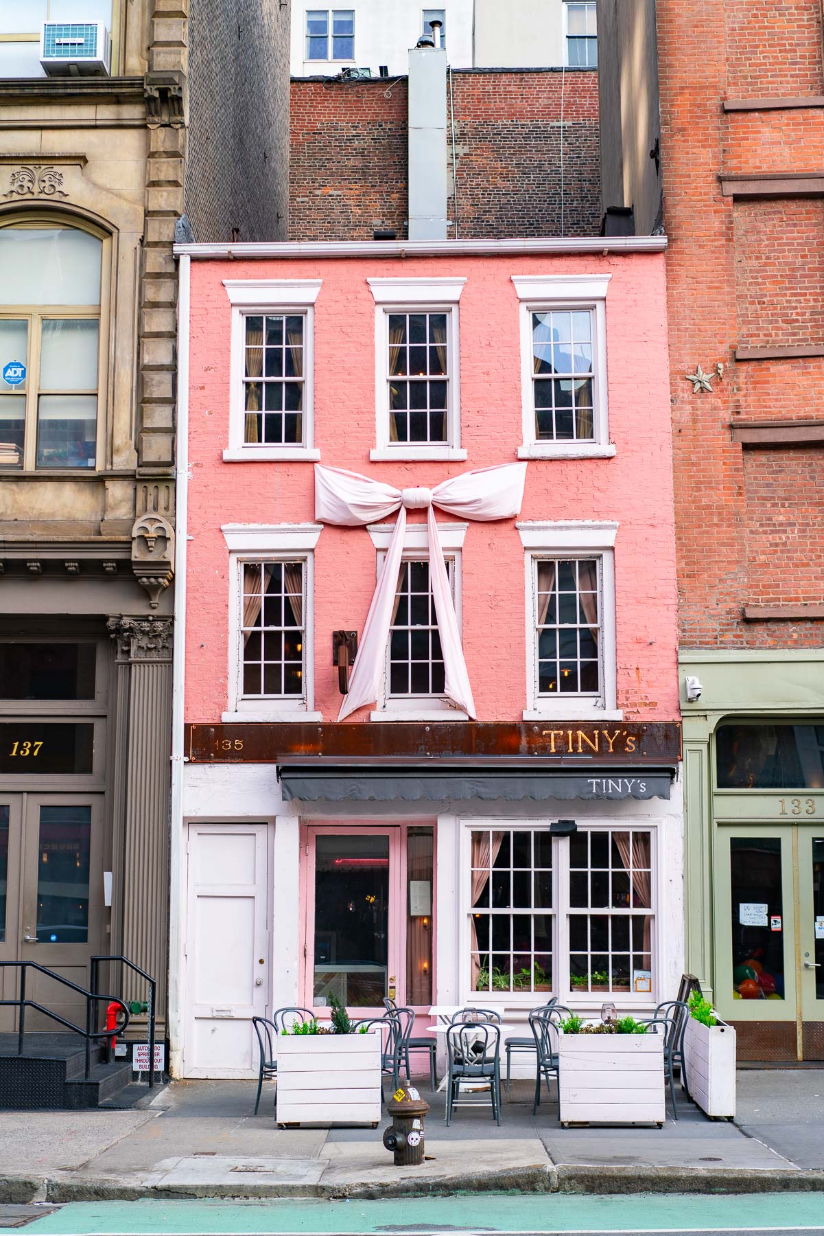 Exterior shot of Tinys Upstairs Bar Tribeca with a pink bow on the outside of the building